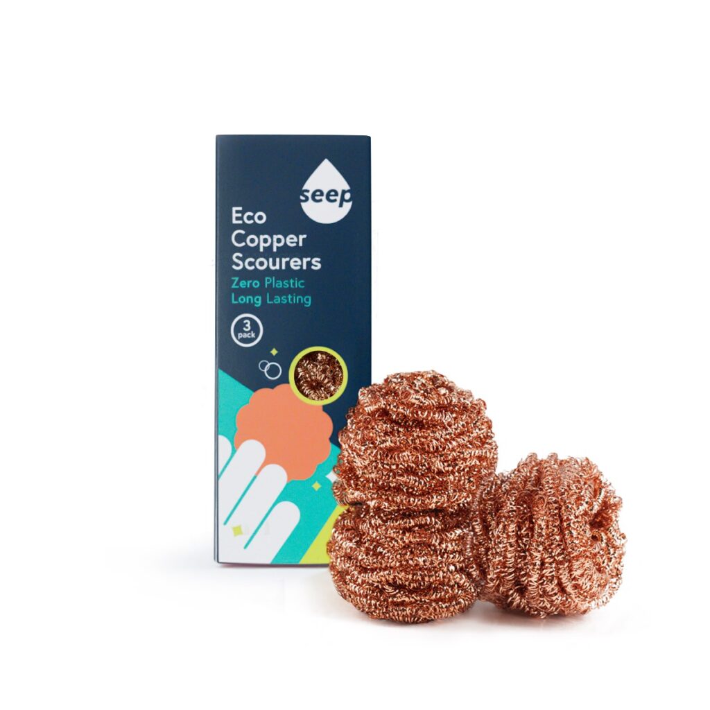 Three Seep copper scourers stacked against each other with the packaging in the background. 