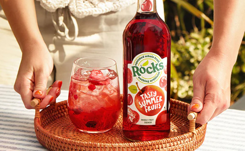 A bottle of Rocks summer fruits squash next to a glass on a drinks tray